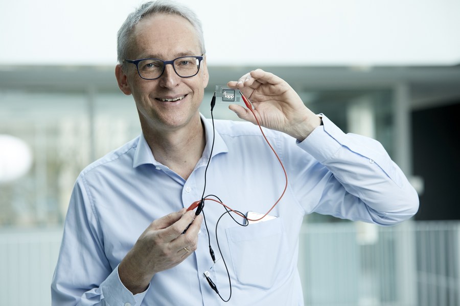 Porträtfoto von Prof. Karl Leo, er hält ein elektronisches Bauelement in der Hand.