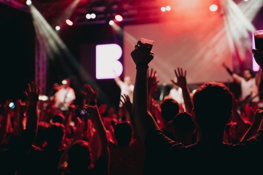 a stage, disco atmosphere, spotlights, people partying and raising their hands in the air